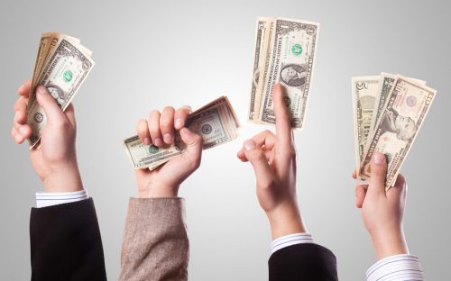 Vier Hände halten Geldscheine zum Crowdfunding in die Höhe.