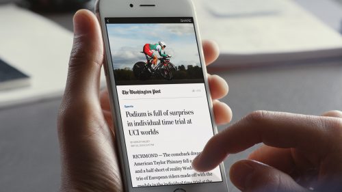 Nahaufnahme eines Smartphones in einer Hand, auf dem ein Artikel der Washington Post gelesen wird.