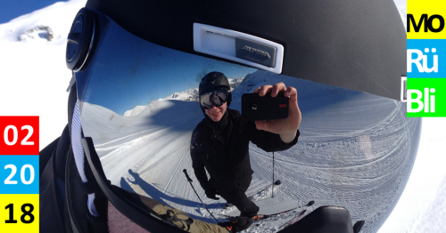 Ein Skifahrer nimmt ein Foto im spiegelnden Visier eines anderen Skifahrers auf.